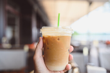 Man hand holding cold Frappe Coffee at a beverage shop, a coffee shop, vintage style.