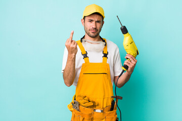 young adult hispanic man feeling angry, annoyed, rebellious and aggressive. worker and drill concept