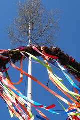 The ribbons of a Maypole blowing in the wind against a clear blue sky 