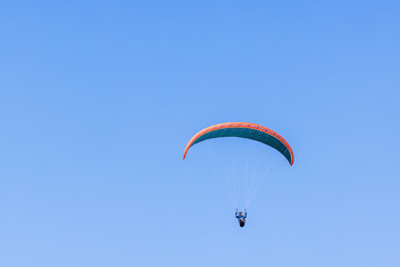 Paraglider flying high up at a blue sunny sky