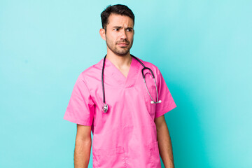 young adult hispanic man feeling sad, upset or angry and looking to the side. veterinarian concept