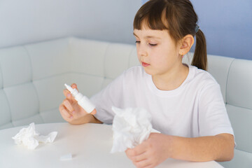 Fototapeta na wymiar Nasal spray bottle and paper tissue in girl hands. Allergy, viral and bacterial sinusitis treatment