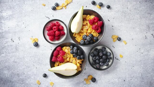 Golden cornflakes with fresh fruits of raspberries, blueberries and pear in ceramic bowl