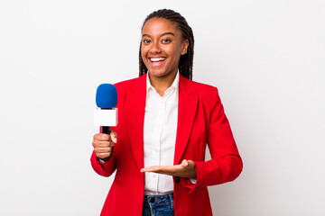 young adult black woman smiling cheerfully, feeling happy and showing a concept. presenter and...