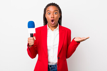 young adult black woman looking surprised and shocked, with jaw dropped holding an object....