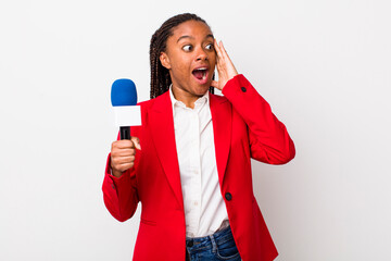 young adult black woman feeling happy, excited and surprised. presenter and microphone concept