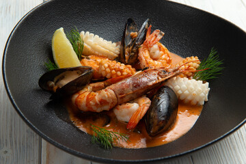 Salad with seafood in a plate on a light background.