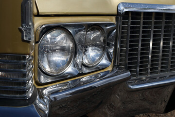 Headlights of  gold classic car, Chrome shining bumper and grill.