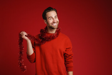 Young man with tinsel laughing and looking at camera