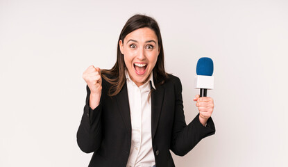 young adult pretty woman feeling shocked,laughing and celebrating success. presenter with a...
