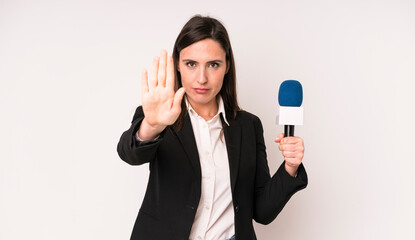 young adult pretty woman looking serious showing open palm making stop gesture. presenter with a...