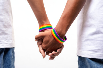 Male couple wearing gay pride rainbow awareness wristbands holding hands on white. lgbt, same-sex...