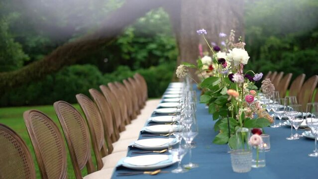 Exquisite spring wedding reception setup with fresh flowers on a long blue table in the garden