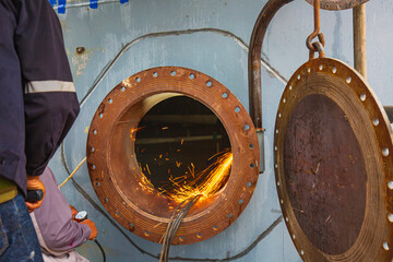 Worker using electric wheel spark grinding on welder metal carbon steel part manhole