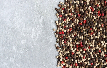 Peppercorns on a table. Light grey background with copy space. Colorful photo of spices. 