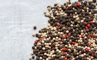 Peppercorns on a table. Light grey background with copy space. Colorful photo of spices. 