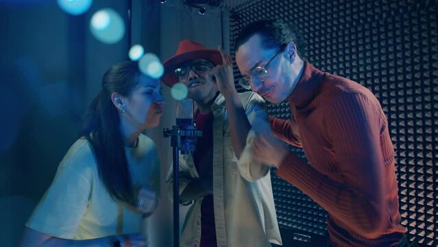 A group of people are singing and being recorded in the studio