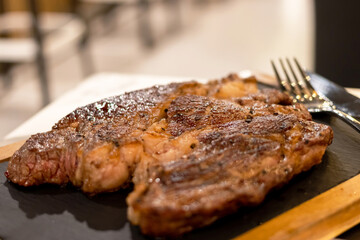 Grilled marble meat steaks chuck eye roll serving on stone black plate.
