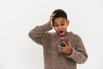 Black preteen boy expressing surprise while using cellphone