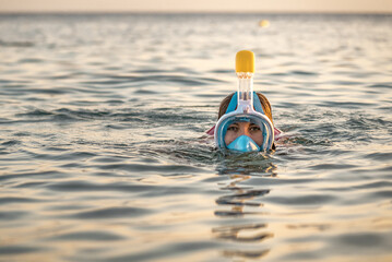 Woman in full face snorkeling mask in sea near coral reef. - obrazy, fototapety, plakaty