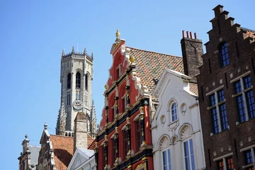 Deurstickers Mooie oude gevels met trapgevels en het Belfort tegen een blauwe lucht in de zon in de steegjes van de oude stad Brugge in West-Vlaanderen in België © Martin Debus