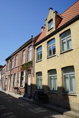 Schöne alte Wohnhäuser in Beige und Naturfarben in einer Gasse mit Kopfsteinpflaster vor blauem...