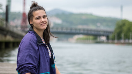 smiling girl sitting in front of the river