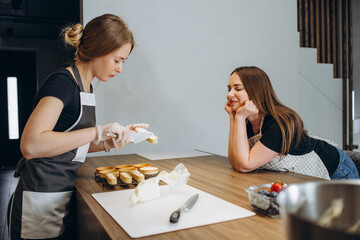 two girls are preparing sweet cakes in the kitchen