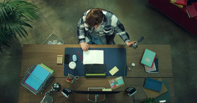 Cinematic top view shot of young male graphic designer or architect is working on his new project in modern creative studio.