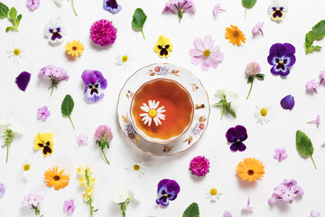 Herbal tea in a vintage porcelain mug with spring and summer flowers on white background. Flat lay,...