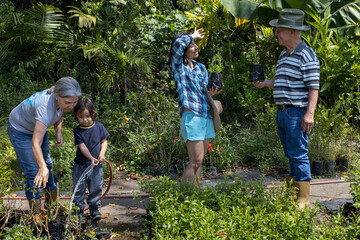 Gardening with children. Grandparents with their daughter and Latin American grandson work in their home garden. Hobbies and leisure, lifestyle, family life.