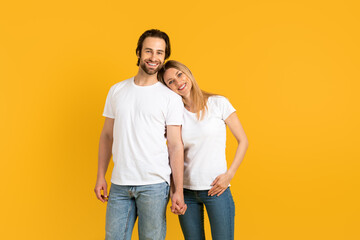 Cheerful handsome millennial caucasian man and woman in white t-shirts hold hands, enjoy moment