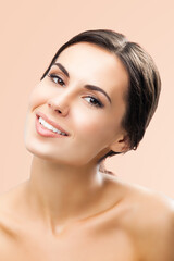 Fototapeta premium Portrait image of beautiful young happy smiling brunette woman, with naked shoulders, isolated over beige background.