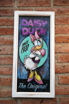 Daisy Duck. Cartoon characters from Walt Disney Pictures Studios. Daisy is Donald Duck's girlfriend. Since 1937. Sign. Poster. Picture hanging on brick wall. Cartoon.
