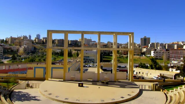 angular image of a coliseum or theater of Romanian or Greek origin  with his magnificence and the capacity against the background of the modern city in Amman Jordan contrasting with it