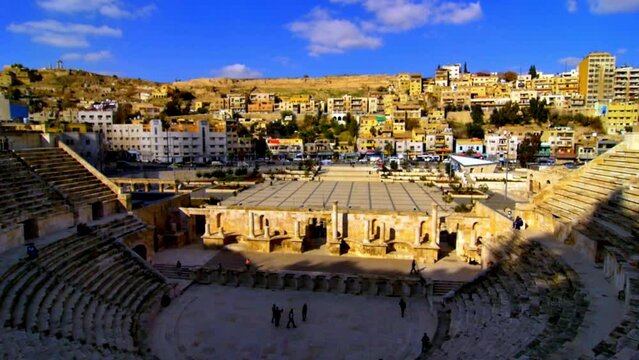 wide angle tilt image of a coliseum or theater of Romanian or Greek origin  with his magnificence and the capacity against the background of the modern city in Amman Jordan on a sunny blue skies day