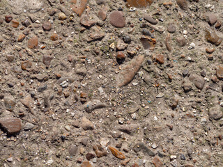 Abstract textured brown background. An old rough texture, a gray concrete slab with small multicolored pebbles and earth
