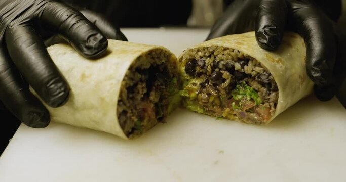 Ched cuts burrito in half and shows it. Mexican food.