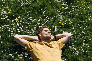 Young man laying in green grass with flowers. People fatigue from work. Summer sleeping and...