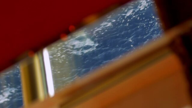 abstract image in a fixed plane where we see the detail of a window inside a cruise ship and in that frame we can see the most pass at a fast speed next to its color is blue and the foam of the cruise