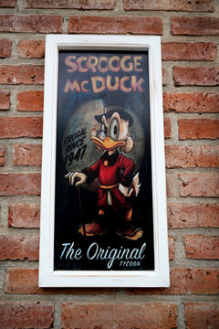 Scrooge McDuck. Rico McDuck. Uncle Rico. Donald Duck's uncle. Cartoon characters from Walt Disney Pictures Studios. Since 1947. Sign. Poster. Picture hanging on brick wall. Cartoon. Penny pincher.