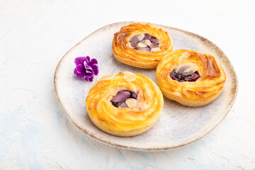 Small cheesecakes with jam and almonds with cup of coffee on a white concrete background. Side view.