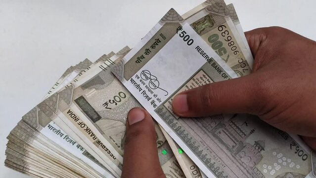 Hand counting bunch of indian currency, money or bank notes bundle of five hundred rupee. Close up 4k macro top view. Financial, savings, economy, business, salary and investment concept background.