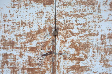 Focus on the key that locks the large, old and rusty door.