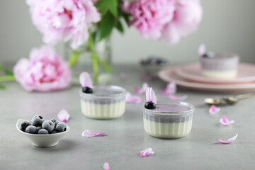 Homemade Italian dessert panna cotta with blue berries and bouquet of peony flowers on gray background. 