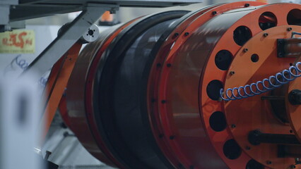 Detailed tyre production technology with modern orange machine moving in factory