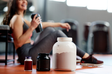 Selective focus on supplements and protein power in gym with a sportswoman. - 504962593