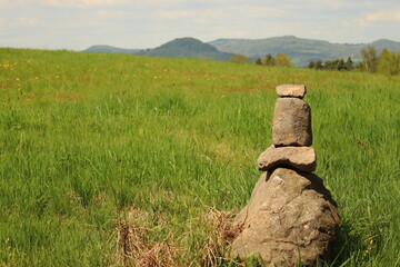 mound of stones in the middle of a meadow on a hill, mountain landscape