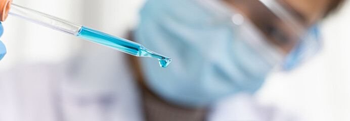 Scientists are carrying blue chemical test tubes to prepare for the determination of chemical...