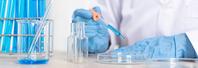 Scientists are carrying blue chemical test tubes to prepare for the determination of chemical...